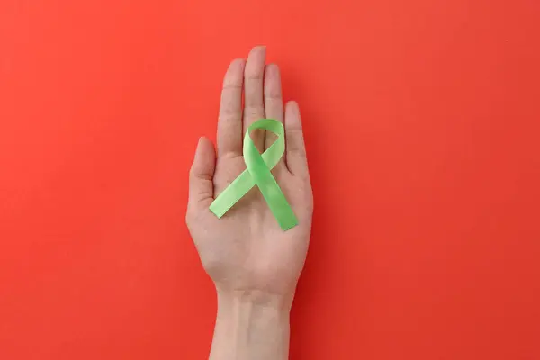 stock image Woman with light green awareness ribbon on red background, top view