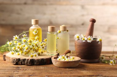 Farklı çiçekler ve ahşap masadaki gerekli yağlar.