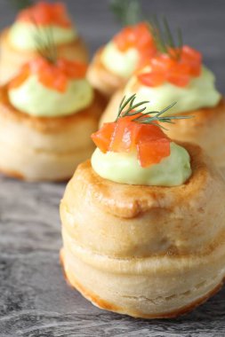 Avokado kremalı lezzetli puf böreği, somon balığı ve dereotu gri masada, yakın plan.