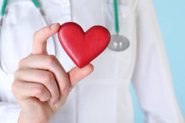 Açık mavi arka planda kırmızı kalpli doktor, yakın plan.