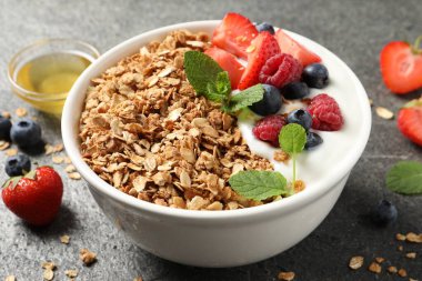 Gri desenli masada meyveli granola ve yoğurt, yakın plan.