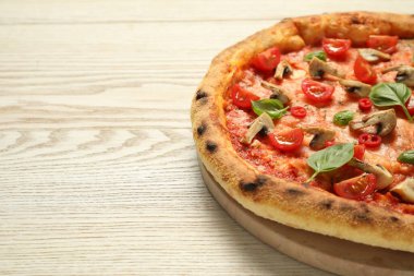Domatesli, mantarlı ve ahşap masadaki fesleğenli lezzetli pizza, yakın plan. Metin için boşluk