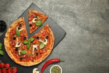 Fesleğenli lezzetli pizza, zeytin ve gri desenli masa malzemesi, düz yatak. Metin için boşluk