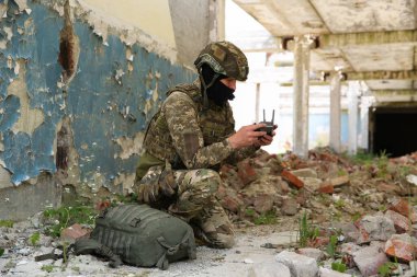 Military mission. Soldier in uniform with drone controller inside abandoned building
