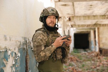 Military mission. Soldier in uniform with drone controller inside abandoned building