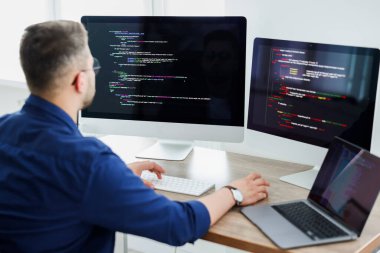 Young programmer working at desk in office, back view