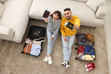 Pasaportları ve biletleri olan çift valizlerin yanında, içeride, en üst katta.