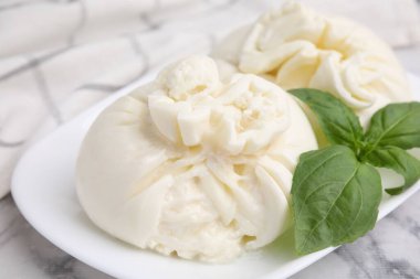 Beyaz mermer masada nefis burrata peyniri ve fesleğen, yakın plan.
