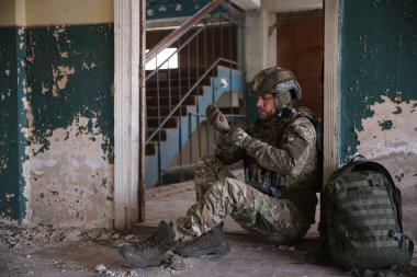 Military mission. Soldier in uniform with drone controller inside abandoned building