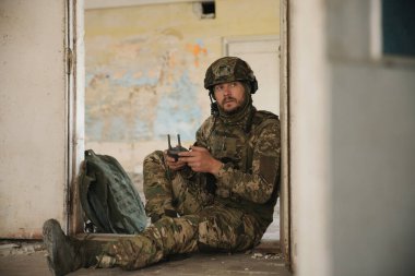 Military mission. Soldier in uniform with drone controller inside abandoned building
