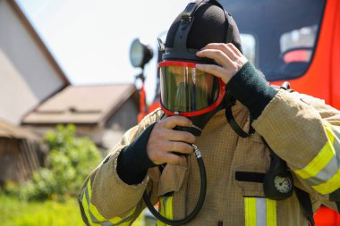 Dışarıda kask ve maske takan üniformalı itfaiyeci.