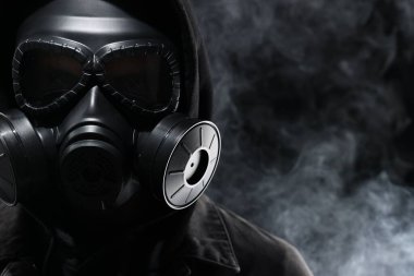 Siyah arka planda duman içinde gaz maskesi takan adam, yakın plan. Metin için boşluk