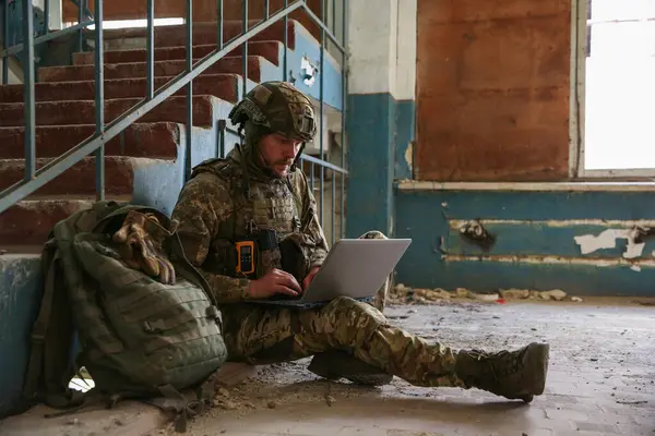 stock image Military mission. Soldier in uniform using laptop inside abandoned building