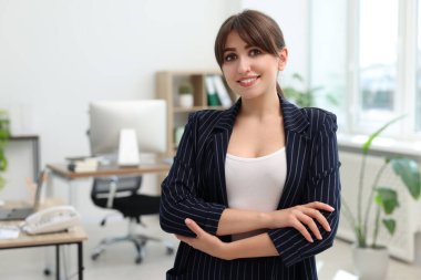 Portrait of smiling secretary with crossed arms in office