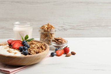 Meyveli tahıl gevreği ve beyaz mermer masada yoğurt, yakın plan. Metin için boşluk