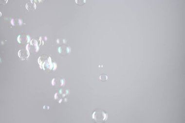 Gri arkaplanda güzel şeffaf sabun köpükleri, metin için boşluk