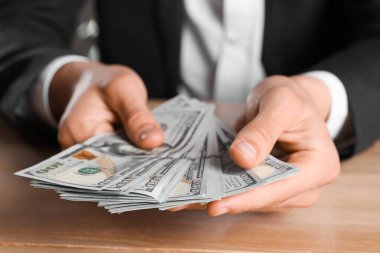 Para değişimi. Ahşap masada dolar sayan adam, yakın plan.