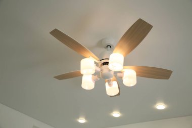 Ceiling fan with lamps indoors, low angle view clipart