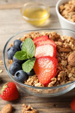 Böğürtlenli, fındıklı ve ahşap masadaki nane aromalı granola.