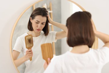 Kapalı alanda saçı dökülmüş fırça tutan üzgün kadın. Alopecia sorunu