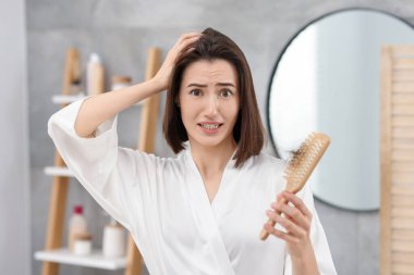 Banyoda saçı dökülmüş, fırça tutan duygusal bir kadın. Alopecia sorunu