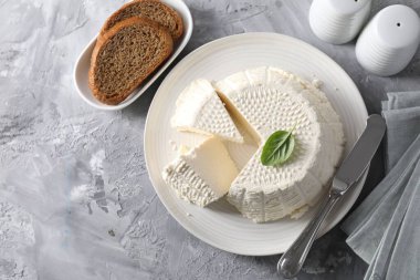 Lezzetli ricotta (krem peynir), gri masada ekmek ve bıçak, düz uzanma