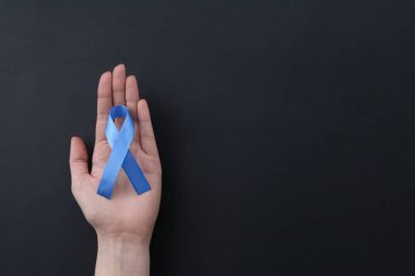 Siyah arka planda mavi farkındalık kurdelesi olan bir kadın. Metin için boşluk
