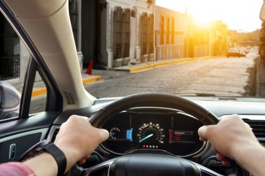 Sürücü koltuğu manzaralı. Direksiyonda el ele tutuşan adam, yakın plan.