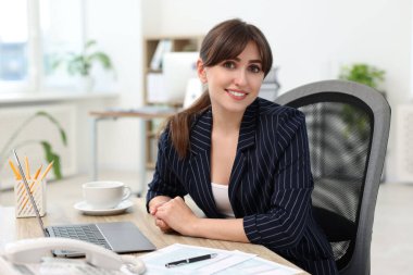 Portrait of smiling secretary at table in office