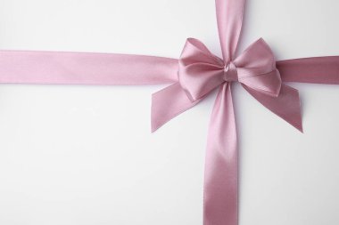 Beyaz arka planda fiyonklu pembe saten kurdele.