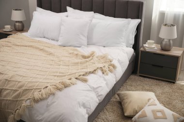 Bir sürü yumuşak beyaz yastık ve örgü örülmüş battaniye.