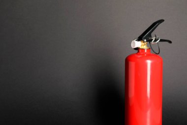 Koyu gri arka planda bir kırmızı yangın söndürücü, metin için boşluk