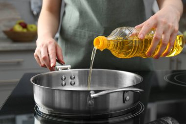 Sebze yağları. Mutfaktaki ocağa yağ döken kadın, yakın plan.