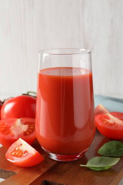 Bardakta domates suyu, fesleğen yaprakları ve taze sebzeler.