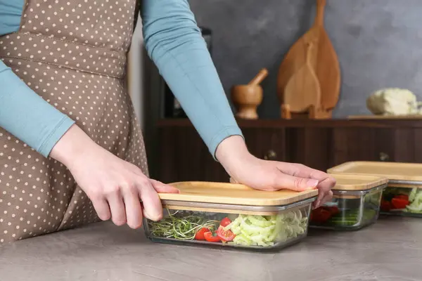 stock image Healthy food. Woman closing glass container with fresh vegetables at grey table, closeup