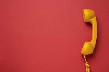 Kırmızı arka planda turuncu telefon, üst manzara. Metin için boşluk