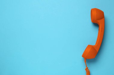 Açık mavi arka planda turuncu telefon ahizesi, üst manzara. Metin için boşluk