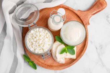 Farklı süt ürünleri ve beyaz mermer masa üzerinde nane şekeri.