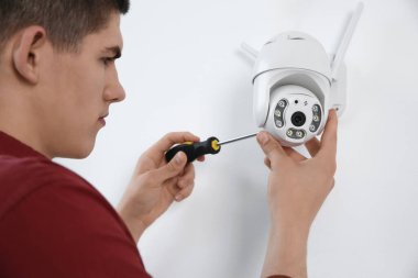 Tornavidalı teknisyen kapalı alandaki duvarlara kamera yerleştiriyor.