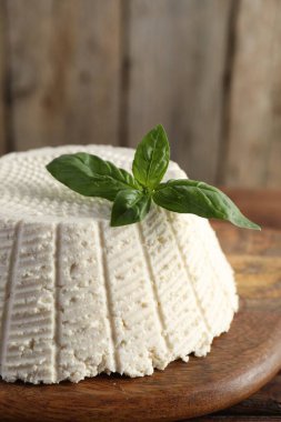 Lezzetli ricotta (krem peynir) ve fesleğen ahşap masada, yakın plan.