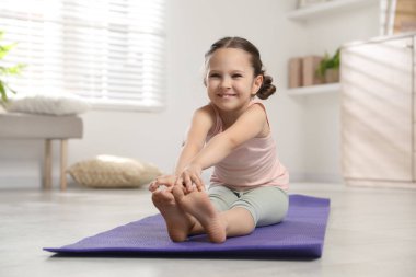 Sevimli küçük kız evde kendini paspasa geriyor.