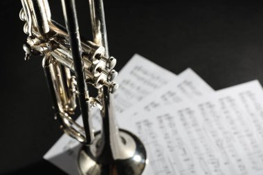 Parlak trompetin yakın görüntüsü ve arka planda müzik kağıtları, metin için boşluk. Rüzgar müzik aleti
