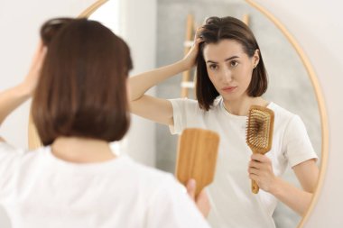 Kapalı alanda saçı dökülmüş fırça tutan üzgün kadın. Alopecia sorunu