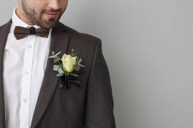 Groom with boutonniere on light grey background, closeup and space for text. Wedding accessory