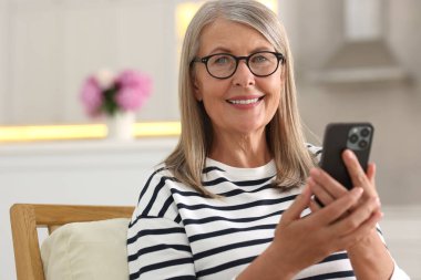 Evde cep telefonu kullanan yaşlı bir kadın.