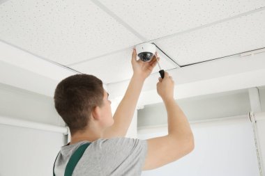 Tornavidalı teknisyen kapalı alanda güvenlik kameraları yerleştiriyor.