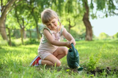 Cute little girl watering tree in garden