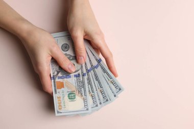 Para değişimi. Bej arka planda dolar banknotları tutan kadın, üst manzara. Metin için boşluk