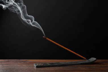 Aromatik tütsü, ahşap masa üzerinde Om işaretleri olan tutacakta için için için yanan çubuk.