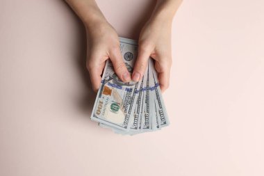 Para değişimi. Bej arka planda dolar banknotları tutan kadın, üst görünüm